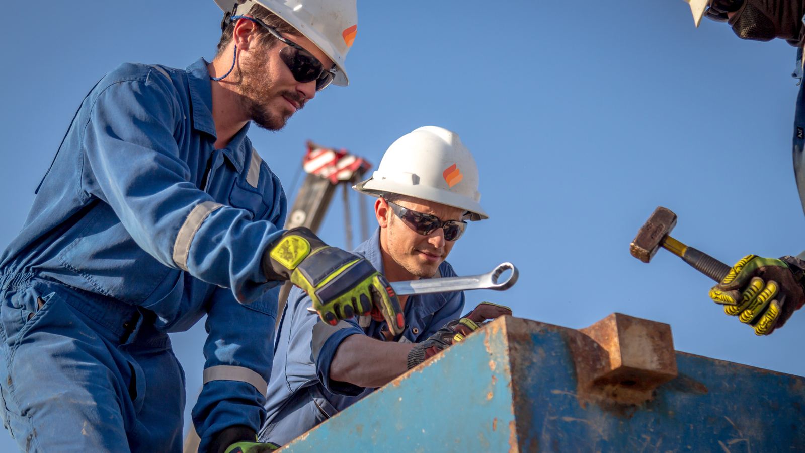 Two field technicians in hard hats and safety glasses working on equipment
